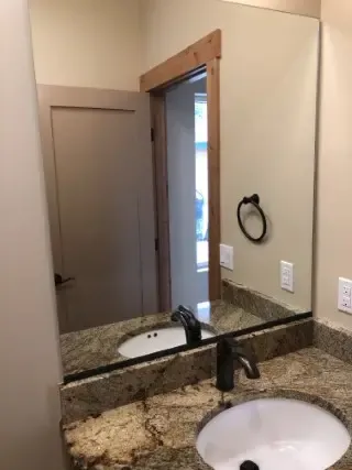 Large rectangular bathroom mirror installed above a granite vanity