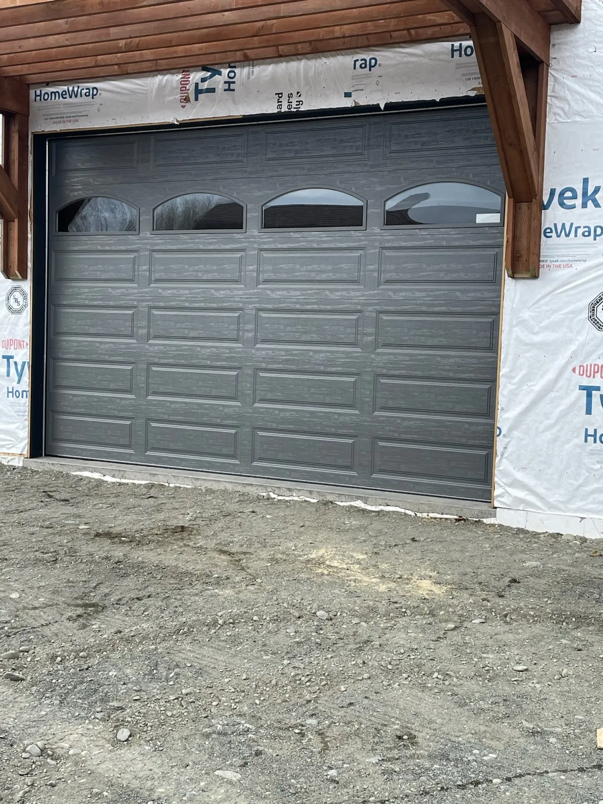 Gray carriage-style garage door installed in a building under construction