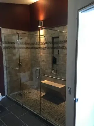 Clear frameless shower enclosure with minimal metal hardware in a tiled bathroom