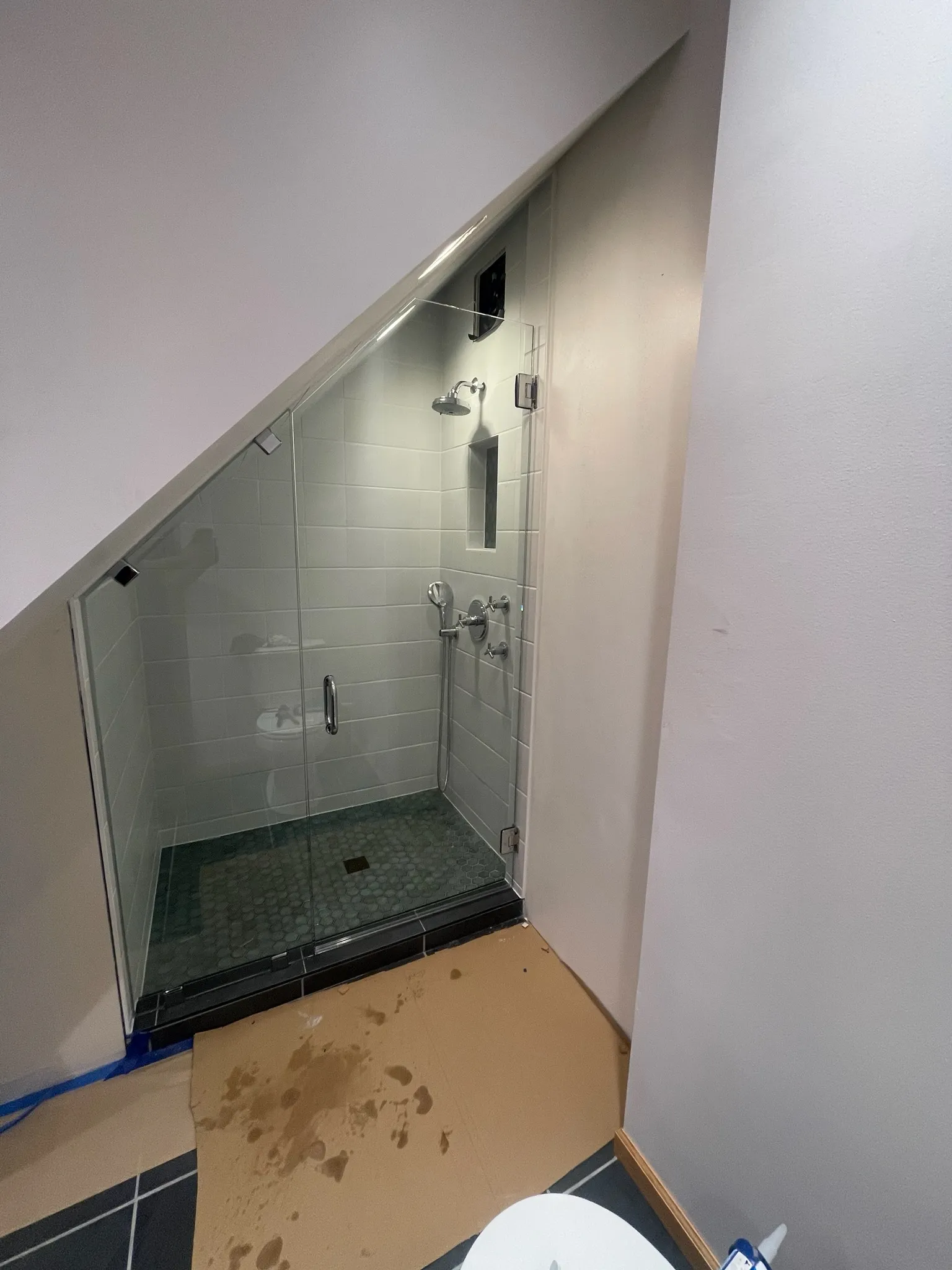 Custom frameless shower enclosure cut to fit beneath a steep sloped ceiling