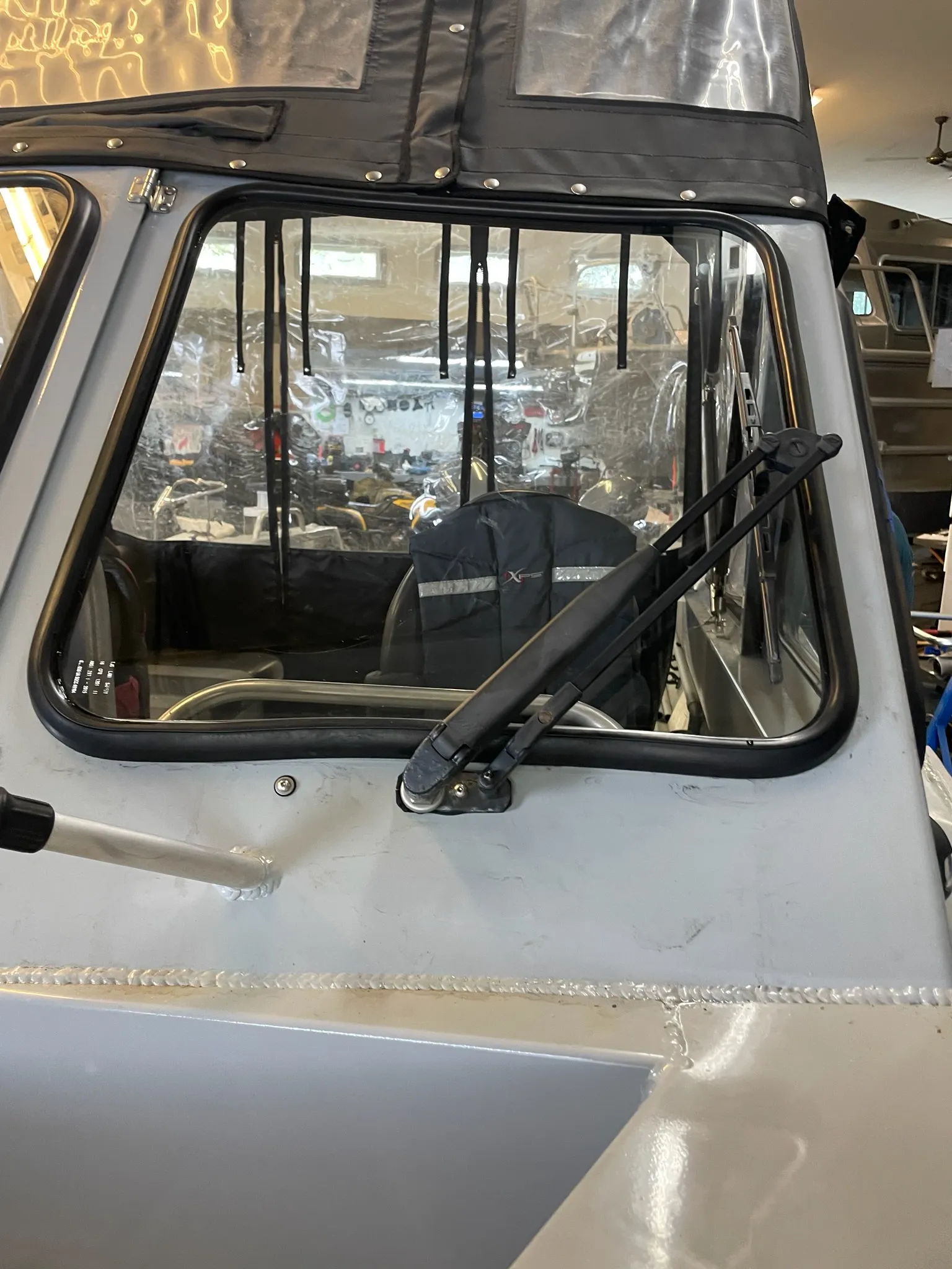 Front windshield glass fitted into an aluminum boat inside a workshop